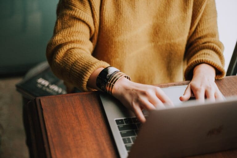 Girl on a computer with a mustard sweater