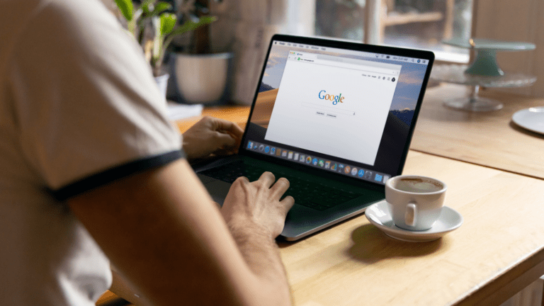 Guy typing on Laptop on the Table with a cup of Coffee